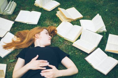 Genç kız çim yalan bir kitap okuma. Bir kız yaz bahçesinde kitaplar arasında