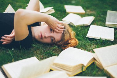Genç kız çim yalan bir kitap okuma. Bir kız yaz bahçesinde kitaplar arasında