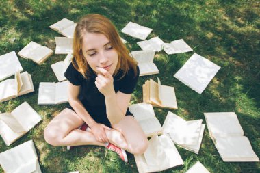 Genç kız çim yalan bir kitap okuma. Bir kız yaz bahçesinde kitaplar arasında