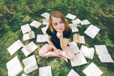 Genç kız çim yalan bir kitap okuma. Bir kız yaz bahçesinde kitaplar arasında