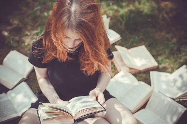 Jong meisje het lezen van een boek tijdens het liggen in het gras. Een meisje tussen de boeken in de zomertuin — Stockfoto