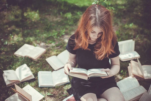 Ung flicka en bok liggande i gräset. En flicka bland böckerna i sommarträdgården — Stockfoto