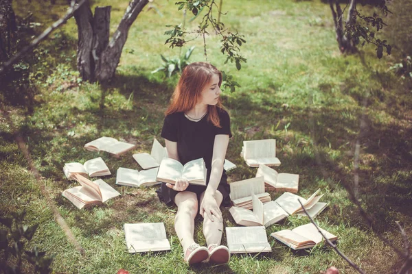 Jong meisje het lezen van een boek tijdens het liggen in het gras. Een meisje tussen de boeken in de zomertuin — Stockfoto