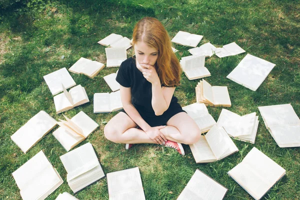 Jong meisje het lezen van een boek tijdens het liggen in het gras. Een meisje tussen de boeken in de zomertuin — Stockfoto