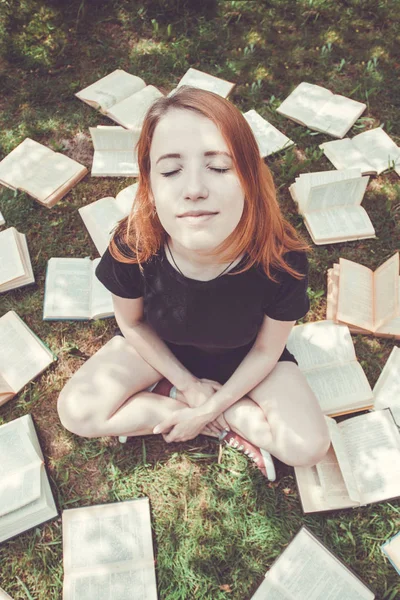 Rapariga a ler um livro enquanto deitada na relva. Uma menina entre os livros no jardim de verão — Fotografia de Stock