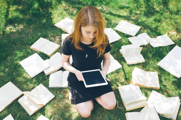 女人的电子书阅读器和书来学习。现代教育技术与传统的方式方法的选择。女孩抱着数字平板电脑和教科书。当代教育. — 图库照片