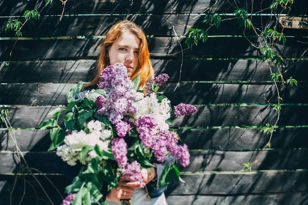 Tjej med en lila bukett i lila i trädgården. flicka Riva lila i trädgården — Stockfoto