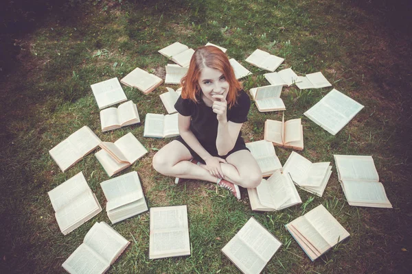 Rapariga a ler um livro enquanto deitada na relva. Uma menina entre os livros no jardim de verão Fotos De Bancos De Imagens Sem Royalties