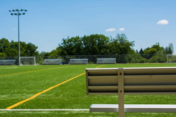 Campo de futebol com banco em um dia ensolarado — Fotografia de Stock