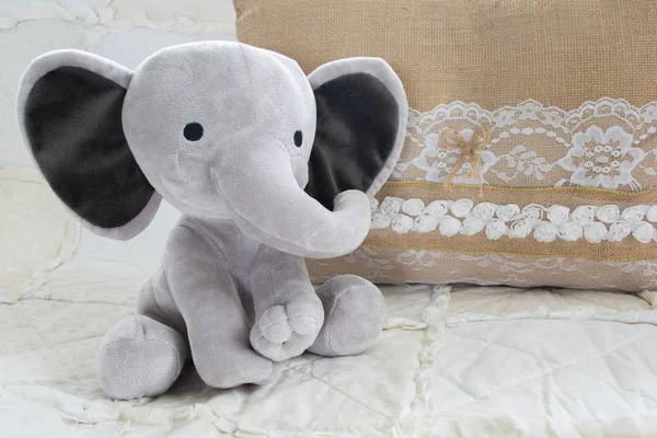 Cute Baby Elephant Stuffed Animal on White Quilt with Burlap Stock Photo