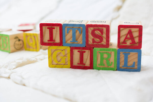 Wooden Alphabet Blocks on Quilt Spelling Its A Girl Angled
