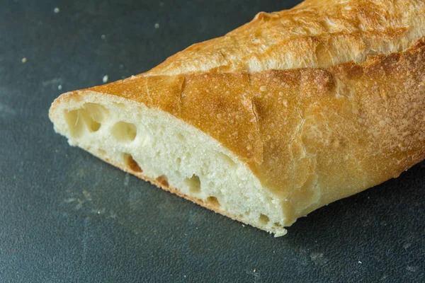 Ekmeği baget siyah yüzey açılı görünümü üzerinde kesmek — Stok fotoğraf
