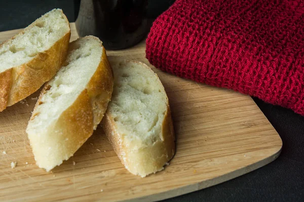 Baguette auf Schneidebrett mit Flasche und Tuch schneiden — Stockfoto