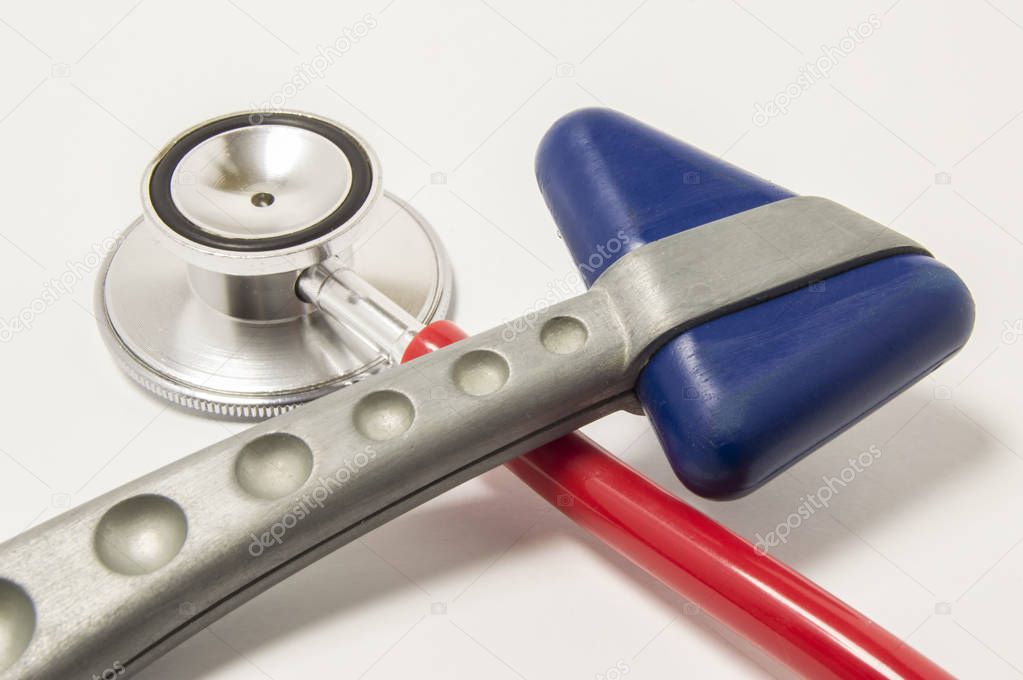 Red stethoscope and neurological reflex hammer with blue triangular head lie crosswise on white background on doctor workplace. Equipment for physical examination in neurology and internal medicine