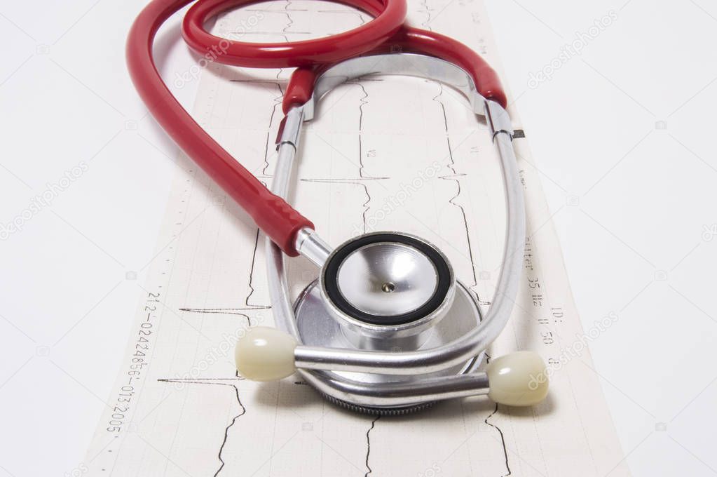 Red stethoscope with chrome details, head in front, lies vertically on three-linear electrocardiogram on white background. Concept photo for diagnosis of disorders in cardiology and internal medicine