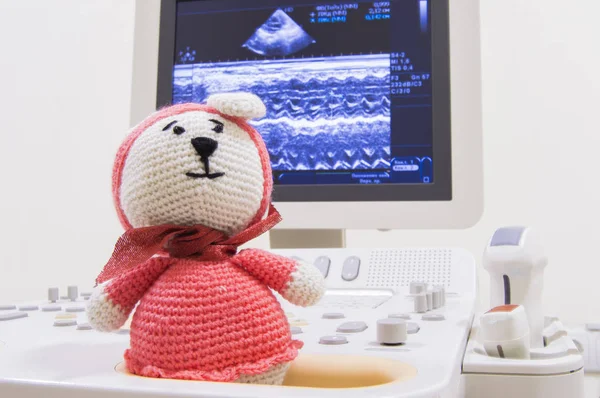 Escáner de ultrasonido médico y conejito de punto de juguete para niños en el fondo de la pantalla con ondas Prueba o escaneo cardíaco ECHO y sondas ultrasónicas. Foto conceptual para el examen por ultrasonido del niño en pediatría —  Fotos de Stock