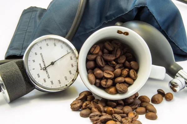 コーヒーと血圧。カップの中のコーヒー豆と、カフや血圧測定の血圧計に囲まれました。影響力と低または高血圧に及ぼすコーヒーのコンセプト — ストック写真