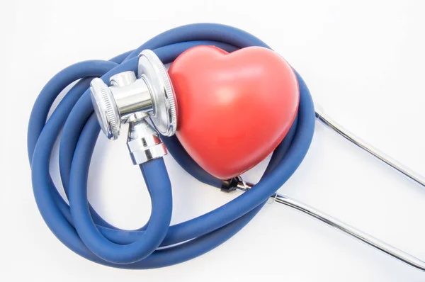 Shape of red heart lies near head of stethoscope, twisted into spiral, on white background top view. Idea photo for diagnostic imaging process in cardiology and treatment of cardiovascular diseases