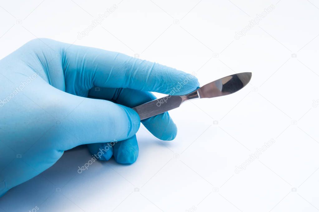 Hand holding scalpel. Palm of surgeon dressed in blue glove holding scalpel. Concept photo for surgeries, procedures, treatment, plastic surgery operation, work of surgical departments and hospitals