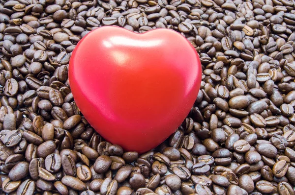 Figure heart is among roasted coffee beans. Effects of coffee and caffeine on heart function, heartbeat, rhythm, and role in development of heartburn, attack, arrhythmia, failure and other diseases — Stock Photo, Image