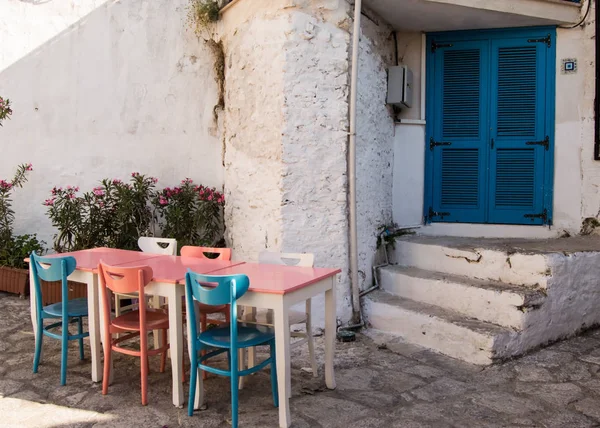 Uliczki i domy Marmaris. Tabela z kolorowe krzesła (niebieskie, różowe, białe) stoi w pobliżu wejścia do domu z niebieski wschód orientalne drzwi wejściowych w starym mieście w kurorcie Marmaris w Turcji — Zdjęcie stockowe