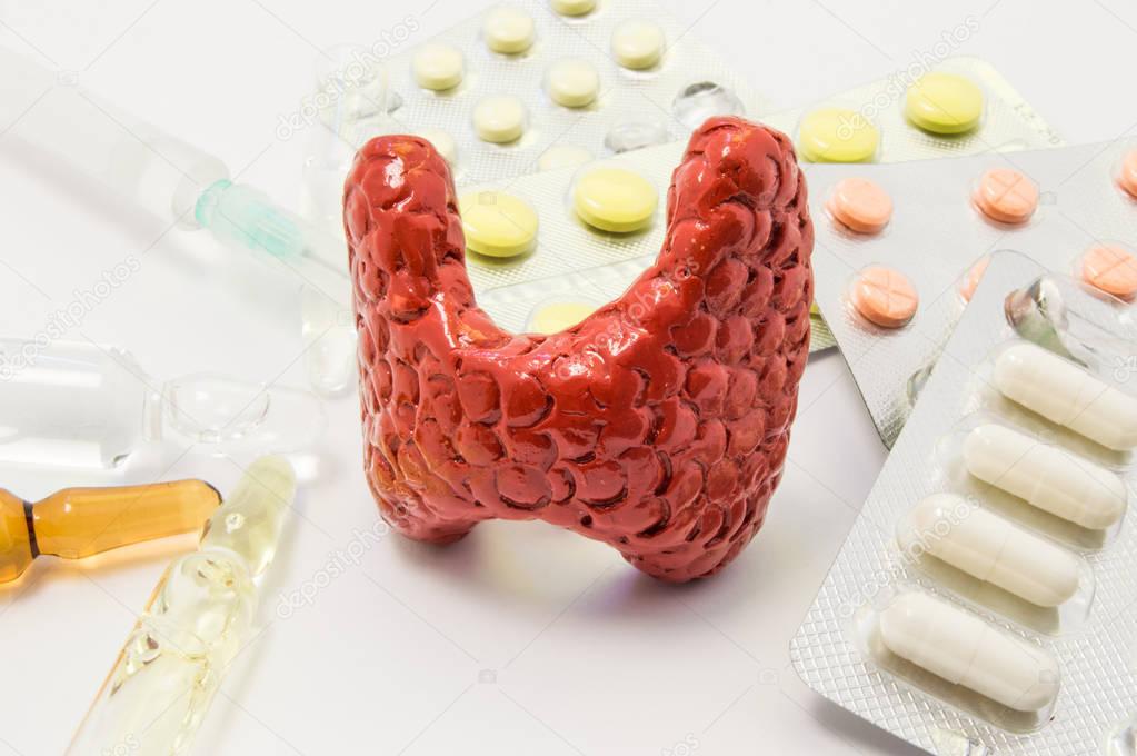 Thyroid treatment concept photo. Figure of thyroid surrounded by pills, medications, medicine vials with syringe, symbolizing treatment, prevention and protection of thyroid gland from diseases 