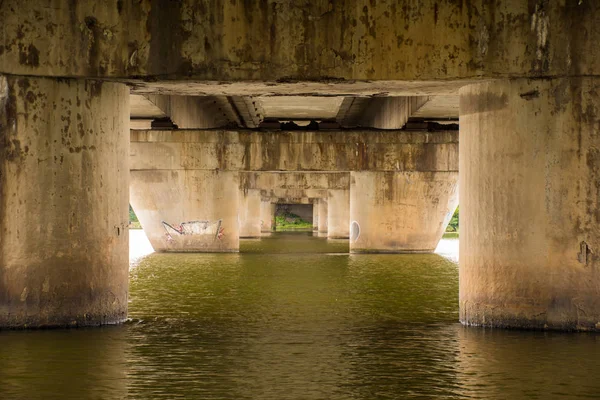 Pylons ou pilar de concreto da ponte na água do rio, de frente uns para os outros de forma recessiva para baixo escalonada como um portal para outro local ou lugar. Foto sob a ponte — Fotografia de Stock
