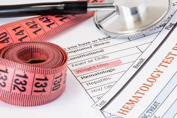 Photo idea of weight loss as symptom or sign of cancer endocrine diseases. Highlighted during doctor consultations title weight loss symptom on patient history next to stethoscope and measuring tape — Stock Image Photo idea of weight loss as symptom or sign of cancer endocrine diseases. Highlighted during doctor consultations title weight loss symptom on patient history next to stethoscope and measuring tape Stock Picture