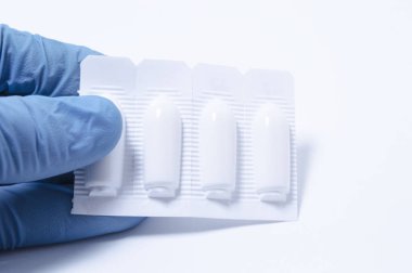 Mavi lateks eldiven giymiş elinde tutan Doktor, ilaçlar, Vakumlu Ambalaj beyaz arka plan üzerinde paketlenmiş tıbbi mum kapatın. Kolorektal cerrahi, Pediatri veya iç hastalıkları kavramı