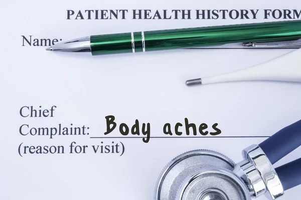 Complaint of Body Ache. Paper health history form, which is written on the patient\'s chief complaint of Body Ache, surrounded by a stethoscope, electronic thermometer and a green ball-point pen