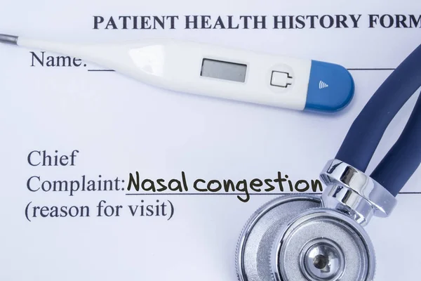 Chief complaint nasal congestion. Paper patient health history form, on which is written the complaint nasal congestion as the main reason for visit to the doctor, with a thermometer and stethoscope — Stock Photo, Image