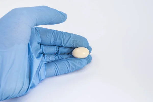 Soft gelatin vaginal tablet or suppository in the hand of the gynecologist, dressed in a blue latex glove. Treatment of diseases of the reproductive organs of women and prevention of women's health — Stock Image Soft gelatin vaginal tablet or suppository in the hand of the gynecologist, dressed in a blue latex glove. Treatment of diseases of the reproductive organs of women and prevention of women's health Stock Image