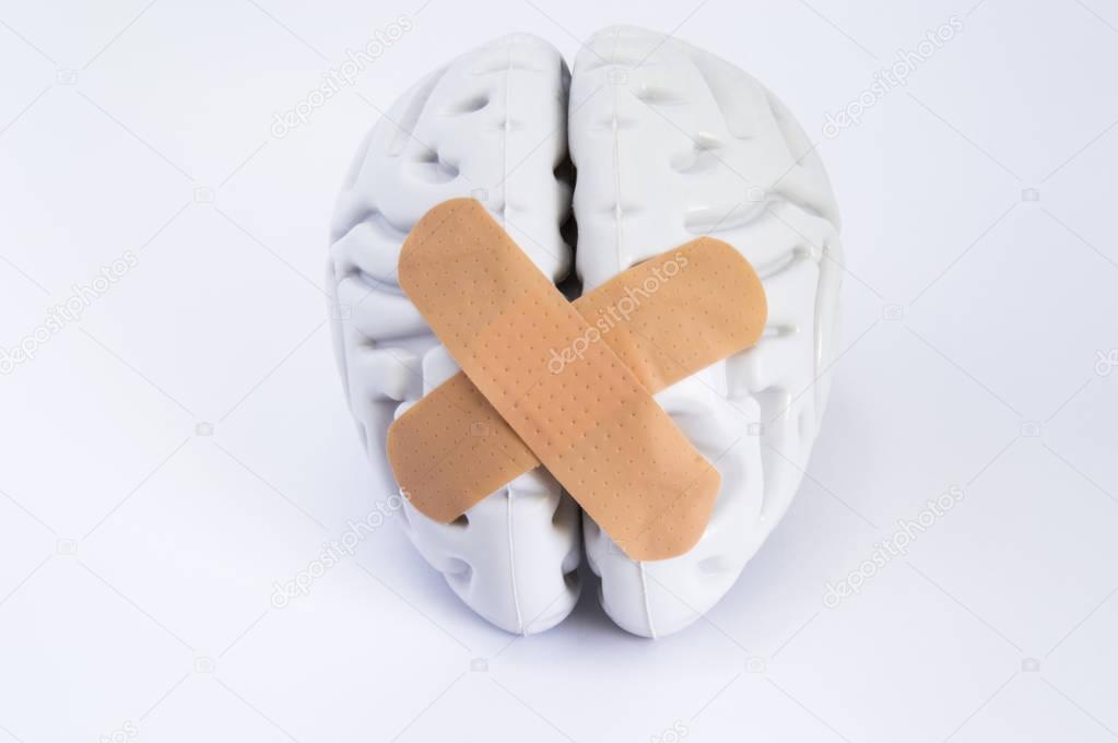 Hemispheres of human brain, stuck together using beige adhesive tape (treatment), lying on white background. Idea for visualizing brain treatment of neurological diseases such as broken brain syndrome