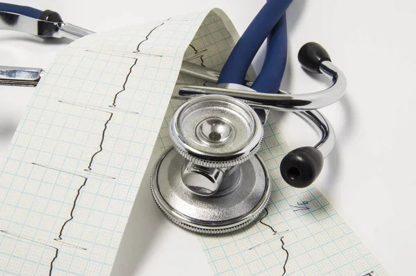 心電図ライン紙と聴診器は医師のオフィスで白いテーブルの上に横たわる。試験や循環器、内科、健康や心の病理を表す診断のためのコンセプト — ストック写真