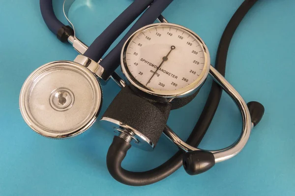 Stethoskop oder Phonendoskop und manuelles Blutdruckmessgerät liegen quer auf blauem Hintergrund in der Arztpraxis — Stockfoto