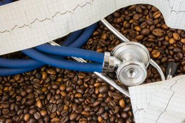 Kahve ya da kafein ve kalp aritmiler (aritmi). Kahve çekirdekleri arka plan üzerinde stetoskop ve EKG bant. Etkisi ve içme kahve veya kafein kardiyak aritmi gelişme riski