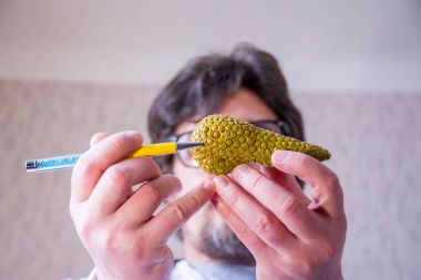 Doktor ufuk arka plan üzerinde onun pankreas bezi, el anatomik model pankreas ön planda üzerinde elinde kalem ile işaret tutar. Patoloji, hastalık veya organ sorunları yerelleştirme