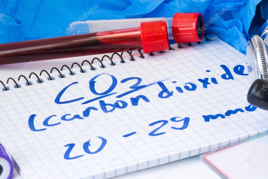 CO2 or carbon dioxide in serum or blood in basic metabolic test. Laboratory test tubes with blood smear, stethoscope or film and gloves are near note with text carbon dioxide on table in doctor office