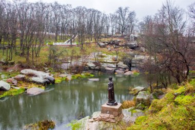 Sonbahar manzara ağaçlar ve Granit kayalar shill yamaç, Uzh Nehri'nin Kanyon ve antik Kiev Prenses Olga Nehri'nin su bronz anıt Drevlyansky park. Sonbaharda Korosten ş.