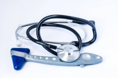 Tıbbi tanı cihazları - steteskop ve genel uygulama bir doktor ofisinde beyaz bir masada yatan nörolojik refleks lastik çekiç