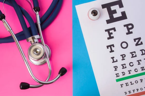 Table for visual acuity test (Snellen chart) and medical stethoscope is in two colors background: blue and pink. Concept of eye diagnosis in men and women, detection of eye diseases in opthalmology