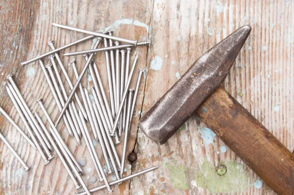 Vintage joiner hammer and nails (hobnails) lying on old wooden table or workbench with splashes paint on it. Tool master carpenter to repair of wood structures, houses, creation of wooden furniture