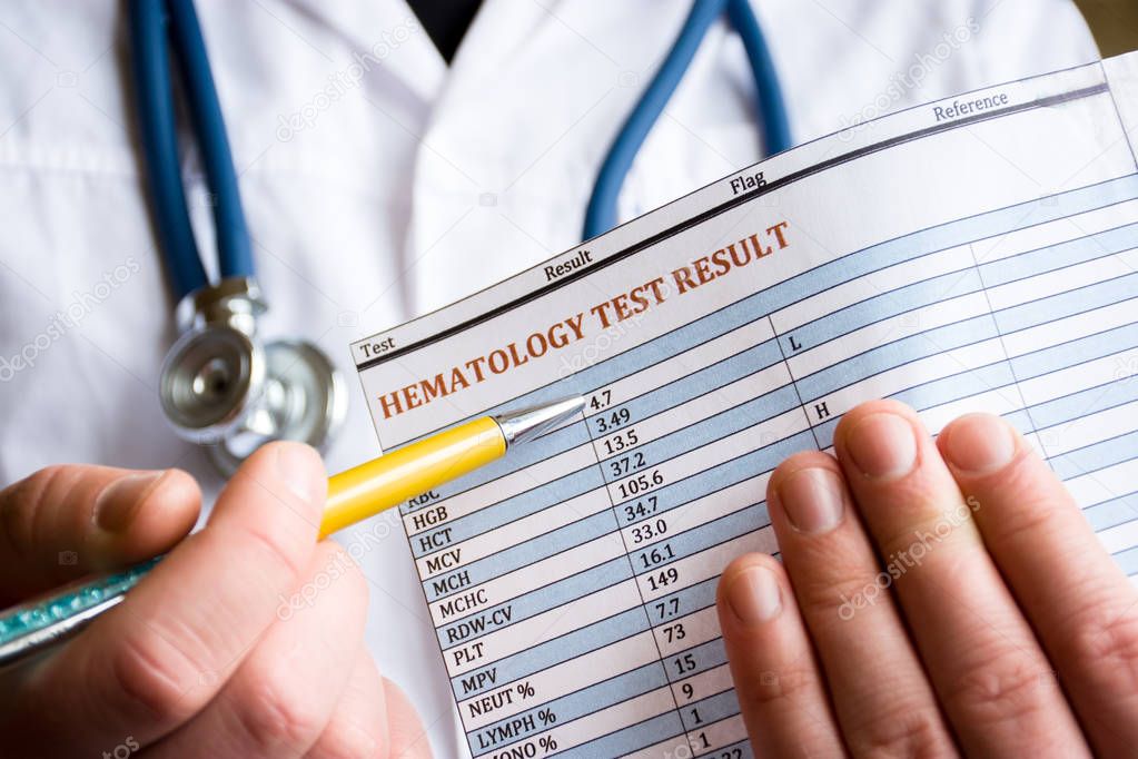 Diagnosis in hematology and hematological blood tests concept photo. Doctor holds in his hand result of blood test and indicates with pen in the other hand on the parameters and performance analysis 