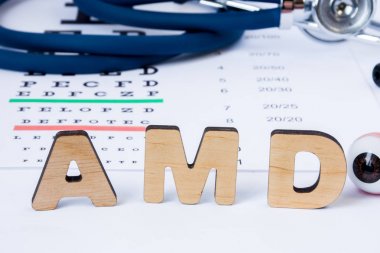 AMD kısaltma veya kısaltma, yaşa bağlı makula dejenerasyonu - yaşlı insanlar göz sorunu. Steteskop ve görme keskinliği testi bulanık arka plan ile ön plan göz model yakınındaki Word Amd açıktır