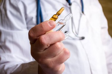 Doctor in medical lab coat holding pharmaceutical vials or ampoule of medicine, offering them patient  on blurred background. Treatment with drug in ampoules via intramuscular or intravenous injection clipart