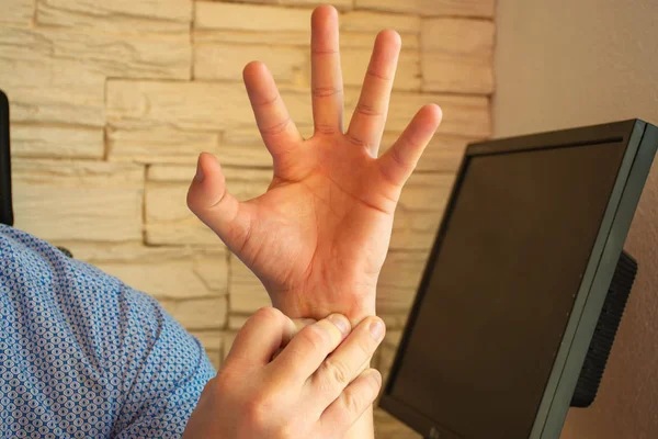 Concept photo of pain in the wrist or forearm, which is accompanied by carpal tunnel syndrome, compression or other nerve or arm joints disease. Man holding on to wrist of other hand, which cramp