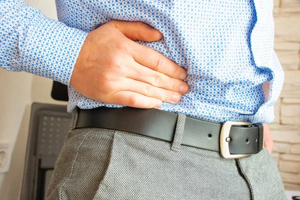 Man holds his hand in area of right lower quadrant of abdomen or bottom of abdomen on right in appendix and colon area due to occurrence of pain. Concept photo of symptoms and signs of appendicitis — Stock Image Man Holds His Hand Area Right Lower Quadrant Abdomen Bottom Stock Photo
