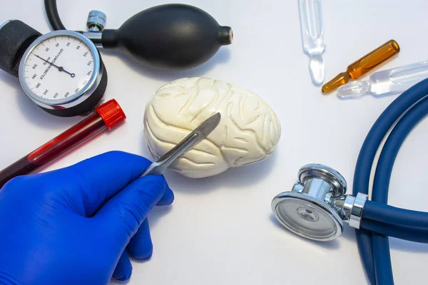 大脑或神经外科的概念性照片 医生手里拿着手术刀 在靠近医疗工具箱的地方做了一个人脑的切口 听诊器 带血的试管 — 图库照片