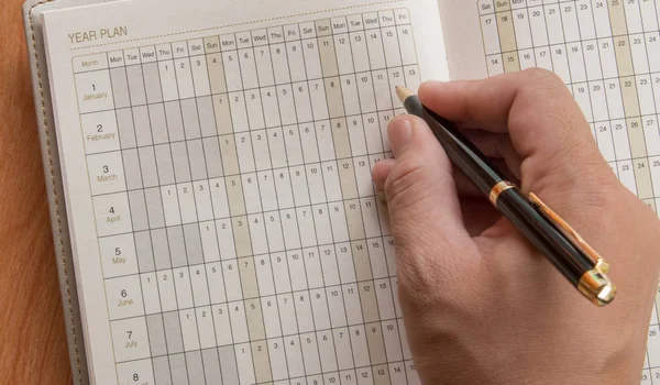 Hand of man marking in open notebook with year plan