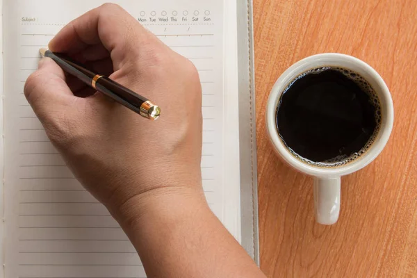 Açık defter fincan kahve, en iyi görünümü ile yazma adamın elini 